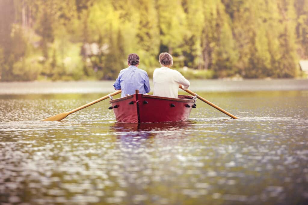 Senior couple paddling on boat with Adirondack mountains in background