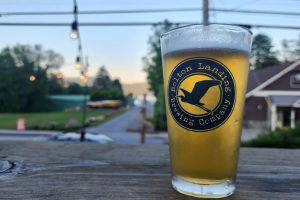 Bolton Landing Brewing Company pint glass with beer overlooking Lake George