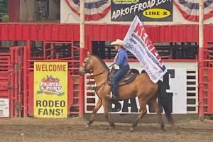 cowgirl riding a horse and holding a flag at the Painted Pony Rodeo